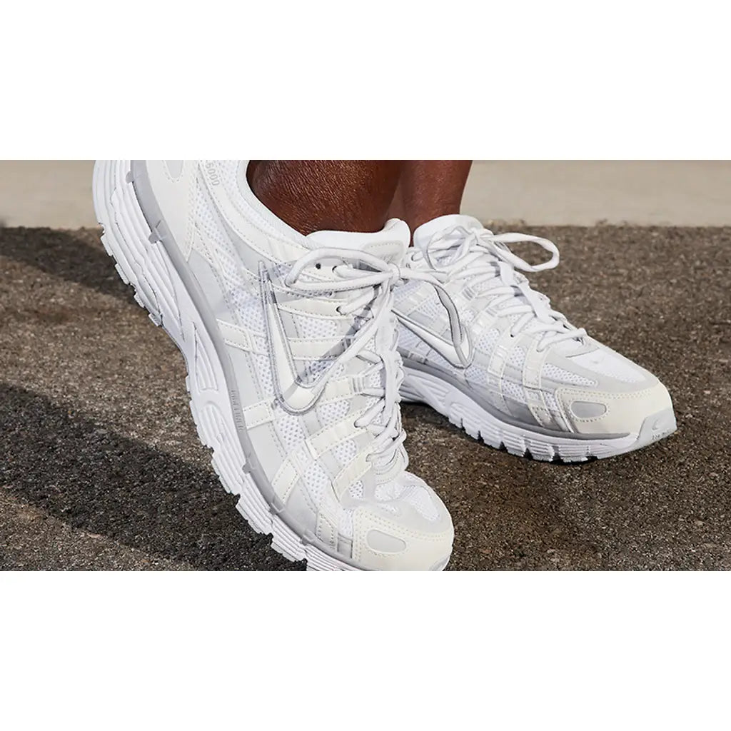 White running shoes on a person's feet with a neutral background