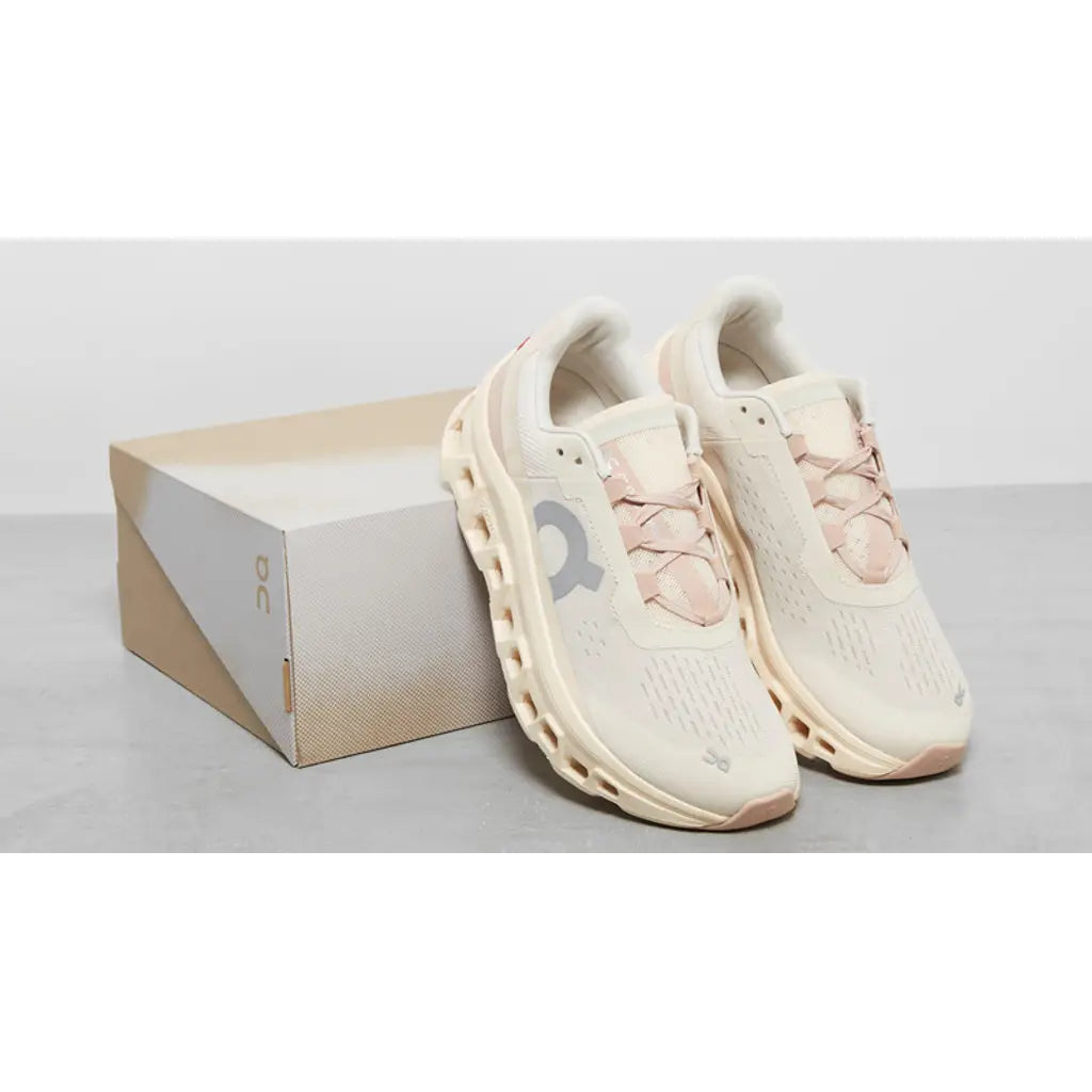 Pair of light pink sneakers with a matching box on a light gray background